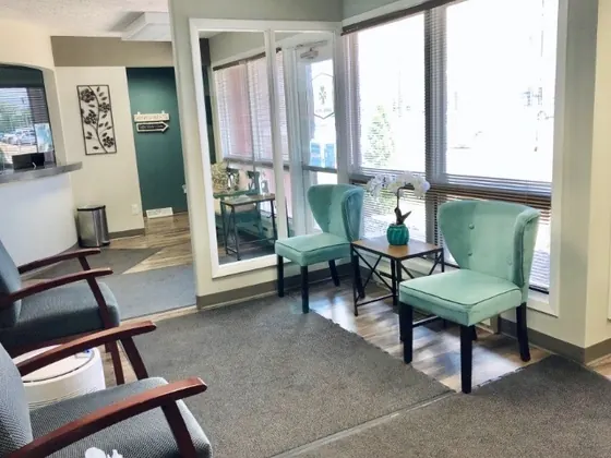 The bright waiting room at Granger Dental Group, with teal armchairs by the windows.