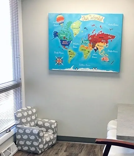 A children's corner with a small armchair and a colorful world map.